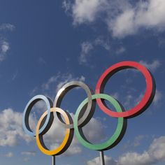 the olympic rings are displayed in front of a cloudy blue sky