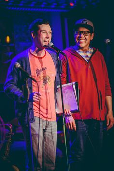 two men standing next to each other on stage with microphones in front of them