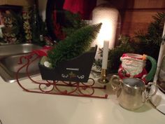 a christmas scene with a sleigh, candle and potted plant on the counter