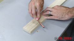 a man is making something with wood and glues it to the table top using a pair of scissors