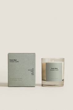 a candle sitting next to a box on a white surface with an empty card in front of it