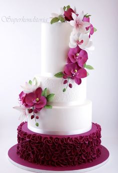 a three tiered wedding cake with purple flowers on top and white icing around the edges