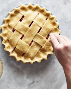 a pie crust is being made on top of a marble table with a hand reaching for it