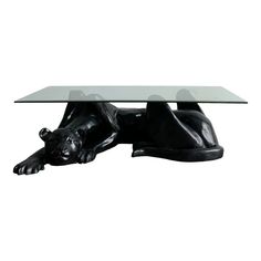 a table with a glass top and a black bear figurine on the bottom