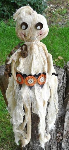 an odd looking stuffed animal sitting on top of a tree stump in the grass with eyes wide open