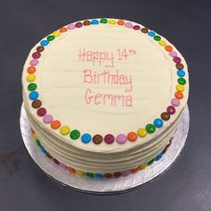 a birthday cake with white frosting and multicolored candies on the top