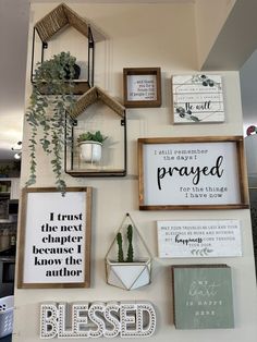 a wall with various framed pictures and signs on it's side, including plants