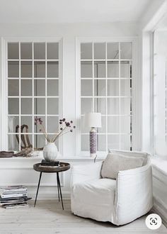 a living room with white furniture and lots of windows