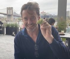 a man is smiling while eating food at an outdoor restaurant