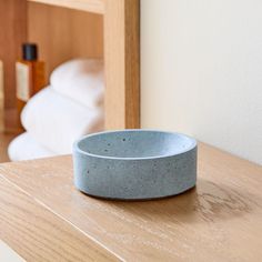 a white and blue bowl sitting on top of a wooden table next to a bed