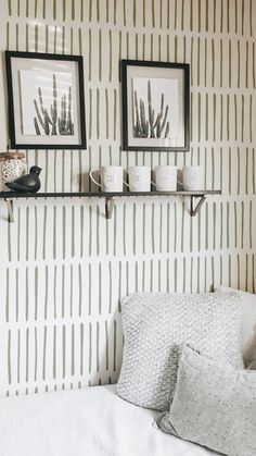 two black and white framed pictures on a wall above a bed with pillows, blankets and throw pillows