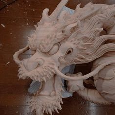 a wooden carving of a dragon with its mouth open and eyes closed on the floor