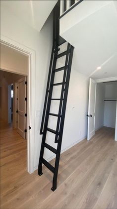 a ladder leaning up against the wall in an empty room with hardwood floors and white walls