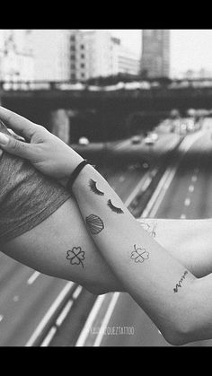 a woman's arm with tattoos on it and an overpass in the background