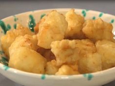 a white bowl filled with tater tots on top of a table