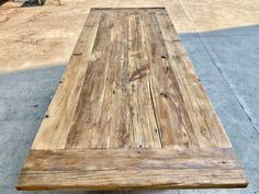 a large wooden table sitting on top of a cement floor next to a parking lot