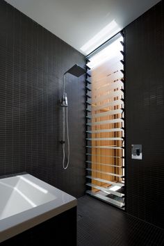 a modern bathroom with black tile and wooden slats on the shower wall, along with a white sink