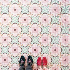 two people are standing in front of a wall with colorful designs on it and one is wearing red shoes