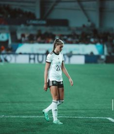 a female soccer player is standing on the field with her foot in the air and looking down