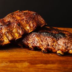 three pieces of meat sitting on top of a wooden cutting board