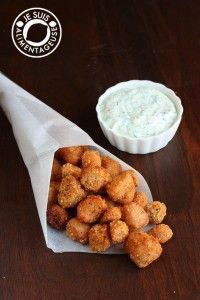 some tater tots are in a paper wrapper next to a bowl of dip