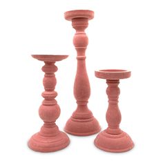 three pink candlesticks sitting next to each other