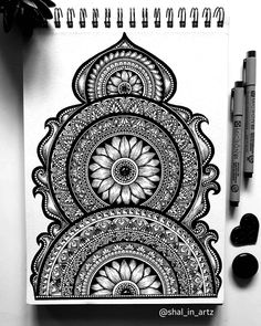 a black and white drawing of an intricate design on paper with marker pens next to it