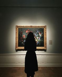 a woman standing in front of a painting with flowers on it's display wall