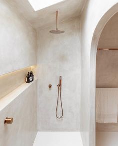 a bathroom with a skylight, shower head and hand held shower faucet