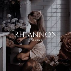 a woman in a white dress sitting on a counter next to flowers and a vase