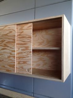 an unfinished wooden cabinet in the middle of a room with blue walls and flooring