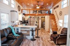 a living room filled with furniture next to a kitchen and loft style ceiling mounted fan