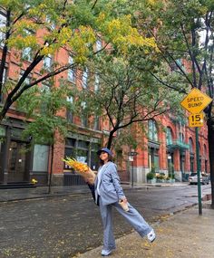 a woman is walking down the street with flowers in her hand