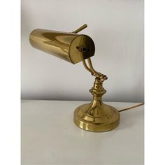 an antique brass desk lamp on a white table