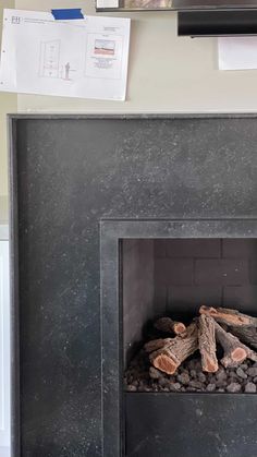 a fire place with logs and papers on the wall