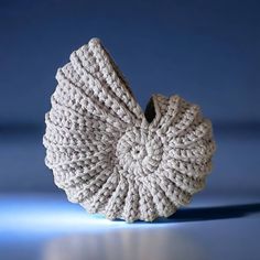 a white knitted object sitting on top of a blue table next to a wall