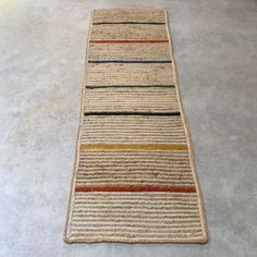 a striped rug is laying on the floor in an empty room with concrete floors and white walls