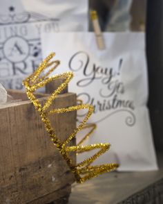 gold glittered christmas tree decoration sitting on top of a wooden box next to a white bag