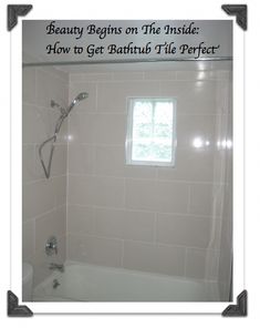 a bath tub sitting under a window next to a shower head mounted on a wall