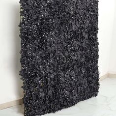 a black square sculpture is shown against a white wall