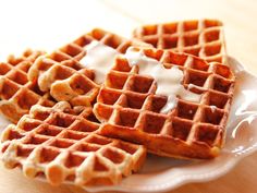 three waffles on a white plate topped with cream