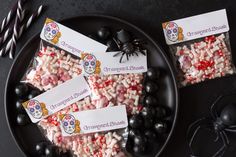 halloween candies are on a black plate with candy and striped straws next to them