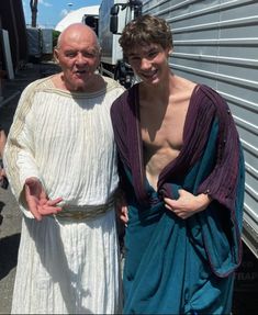 an old man in a robe standing next to a young man dressed up as jesus