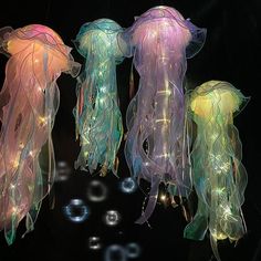 three jellyfish lights hanging from strings with bubbles in the water around them, all lit up