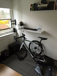 a bicycle is parked next to a window in a room with bookshelves and other items