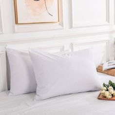 two white pillows sitting on top of a bed next to a tray filled with flowers