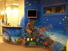 a fish themed wall in an office with a computer monitor on the top of it