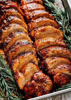 sliced pork roast in a pan with rosemary sprigs on the side, ready to be served