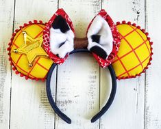 a mickey mouse ears headband with red and yellow decorations on it, sitting on top of a white wooden surface