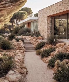 a stone house surrounded by trees and rocks with stairs leading up to the front door